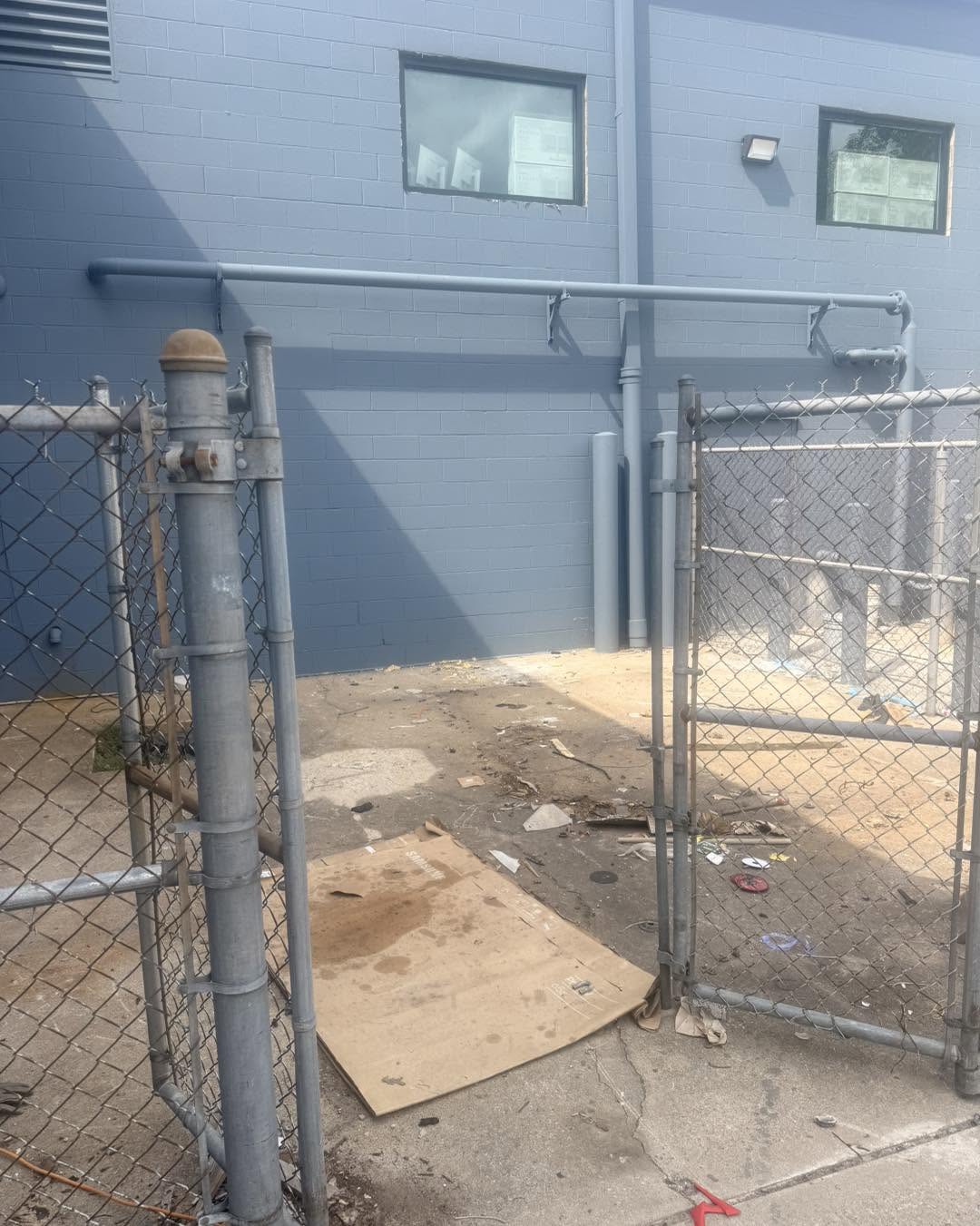 Scattered debris outside a commercial building behind a chain-link fence
