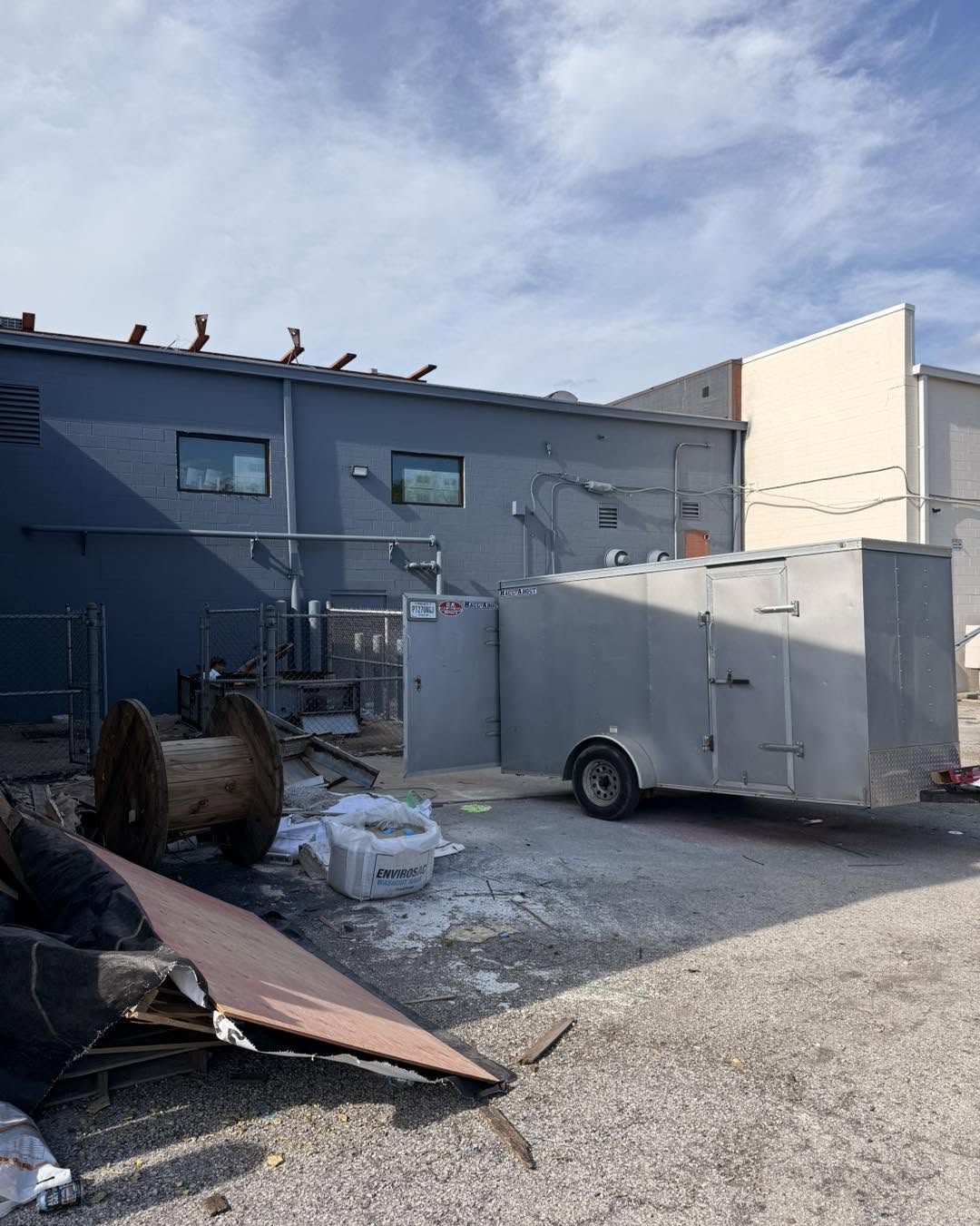Commercial lot with plywood, cable spools, and an enclosed trailer